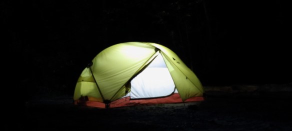 a tent at night, lit from inside by a lantern