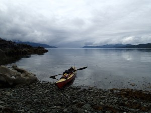 A sea kayak pulled up on a cobble beach.