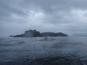 sea kayaker off wave-swept rocks