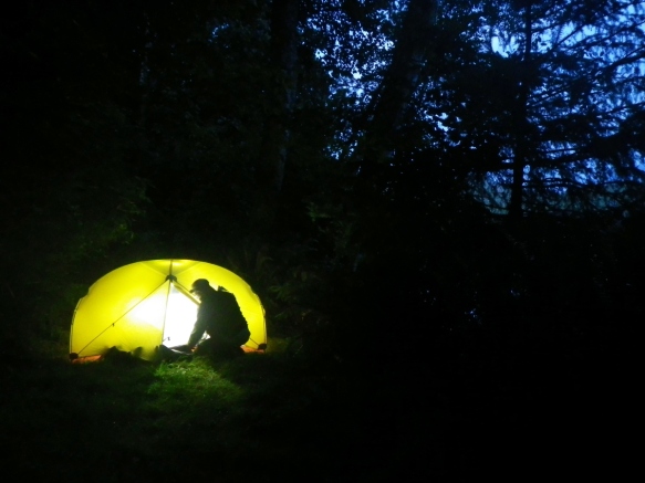 By the light of the moon, a camper enters an iluminated tent