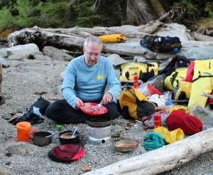 a kayaker cooks steak strips on a campstove