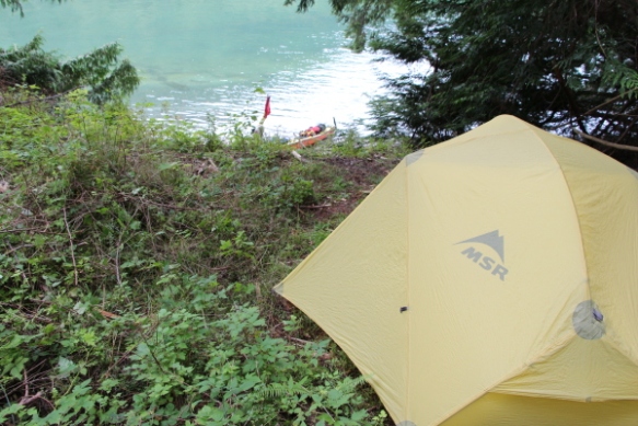 looking over a tent to a sea kayak at the water's edge