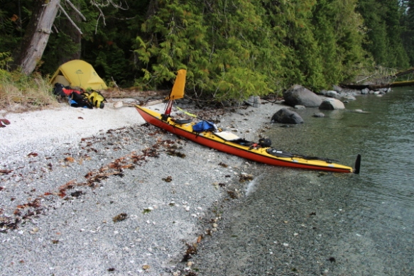 A beached sea kayak with a tent in the background