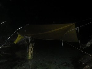 a camping hammock at night suspended over water