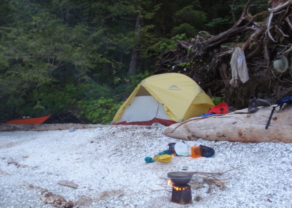 a tent and woodstove on a shell beach