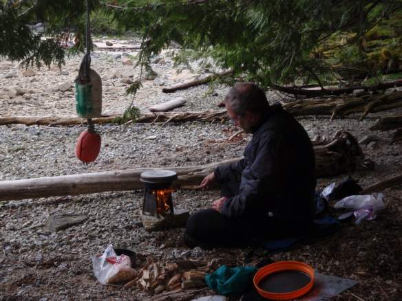 a camper stokes a portable wood-fired campstove