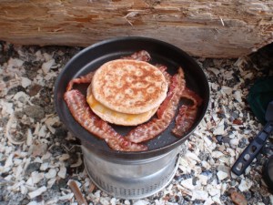 toasted cheese muffins and bacon on a campstove