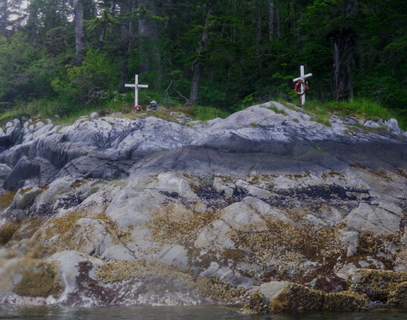 a pair of white memorial crosses on the shoreline