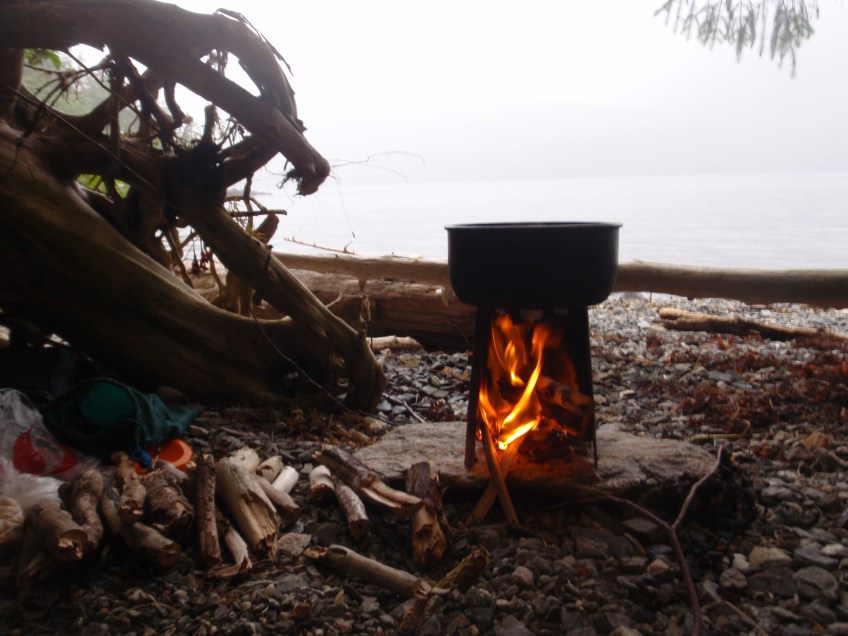 a pot simmers on top of a portable woodstove