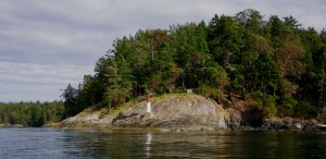 a sea kayak paddles beneath Kanaka Bluff, Portland Island (Princess Margaret Island) Gulf Islands National Park