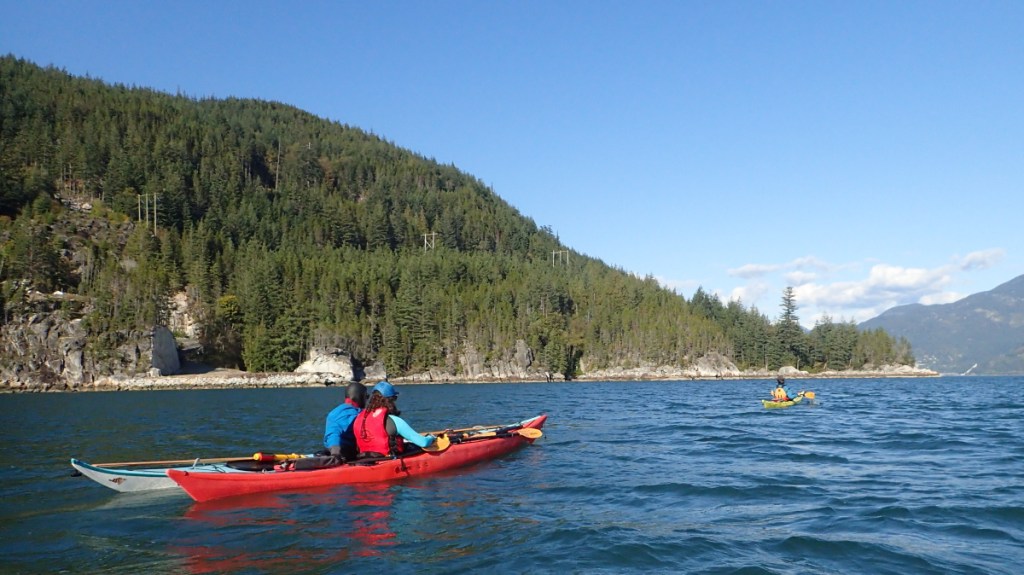sea kayak rescue practice: as one rescuer tows a "hypothermic capsize victim" a second rescuer is rafted up with the sometime swimmer to prevent a recapsize.