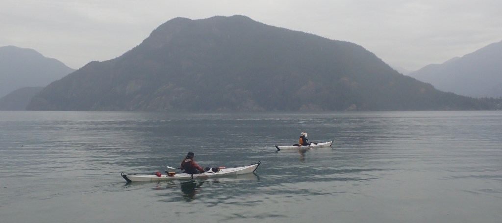 two sea kayakers in Howe Sound, British Columbia, with Anvil Island in the background